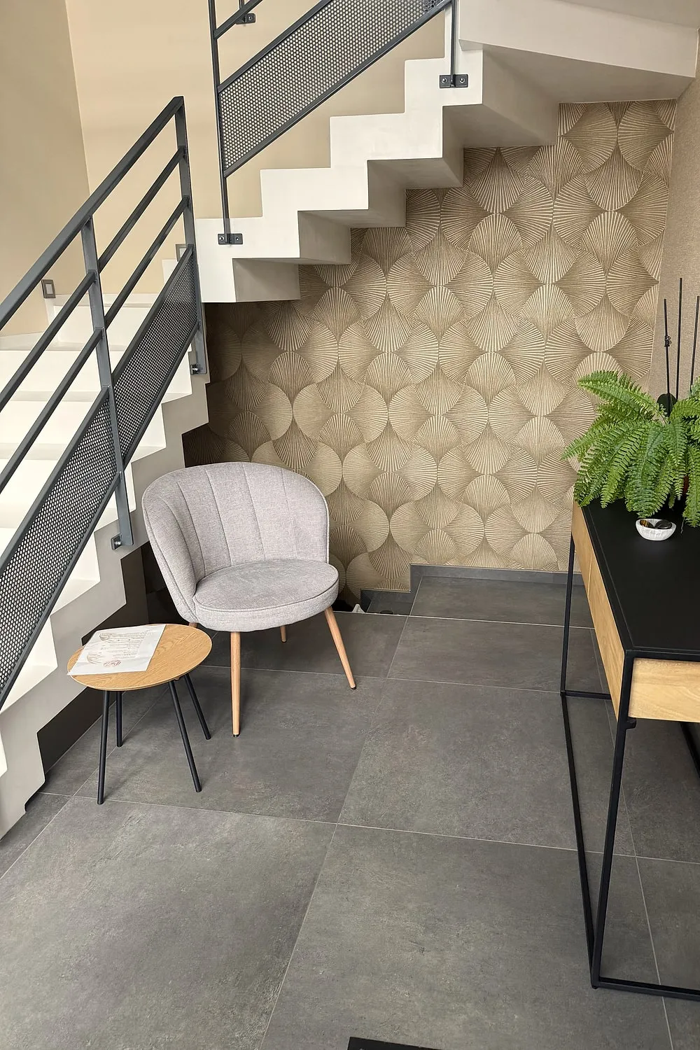 Espace d'accueil avec fauteuil, console et escalier